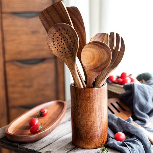 Holz-Küchenutensilien in zylindrischem Halter auf Küchentisch mit Kirschtomaten.