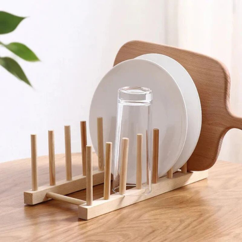 Holzständer mit Tellern und Glasflasche auf Esstisch, natürliches Licht im Hintergrund.