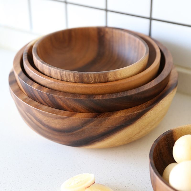 Vier ineinander gestapelte Holzschalen mit heller Maserung auf weißem Tisch.