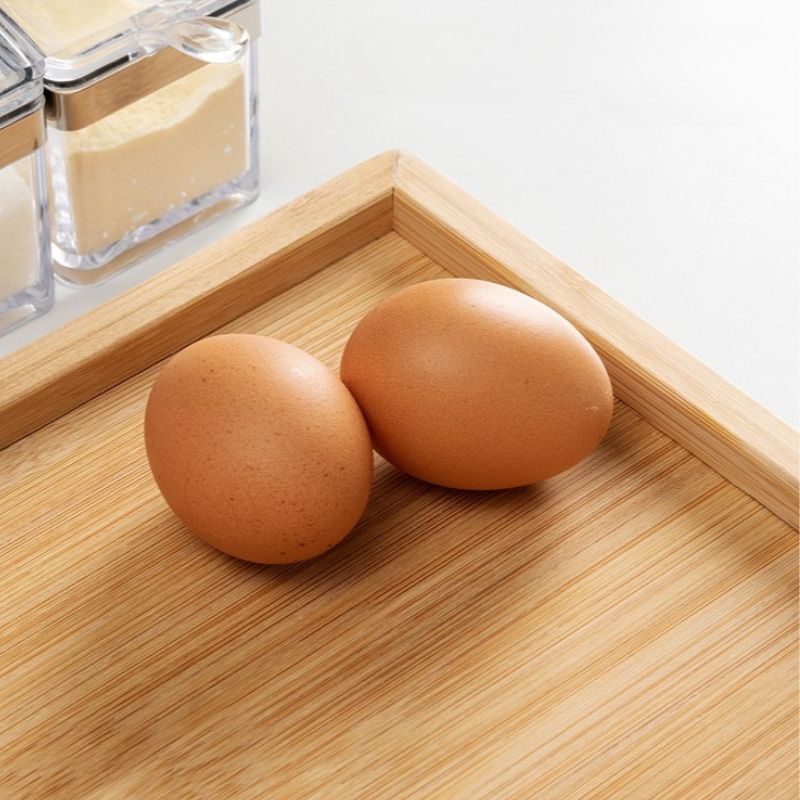 Zwei Eier in der abgeschrägten Ecke eines Holzbretts mit erhöhtem Rand.