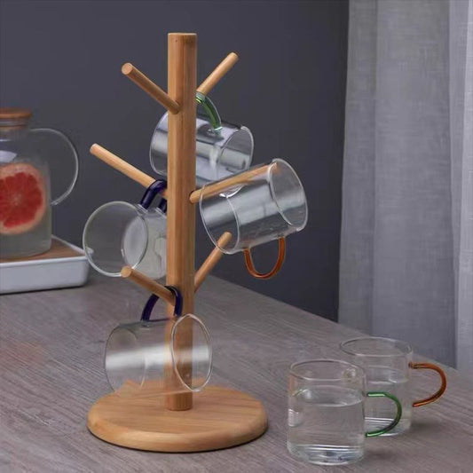 Bambus-Tassenhalter mit sechs Glastassen auf rundem Sockel auf einem Tisch.