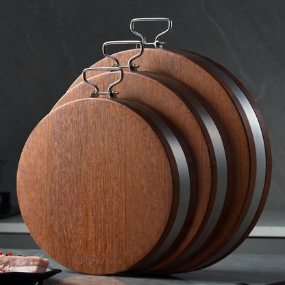 Drei runde Schneidebretter aus Holz mit Edelstahlkante an Wandhaken aufgehängt.

