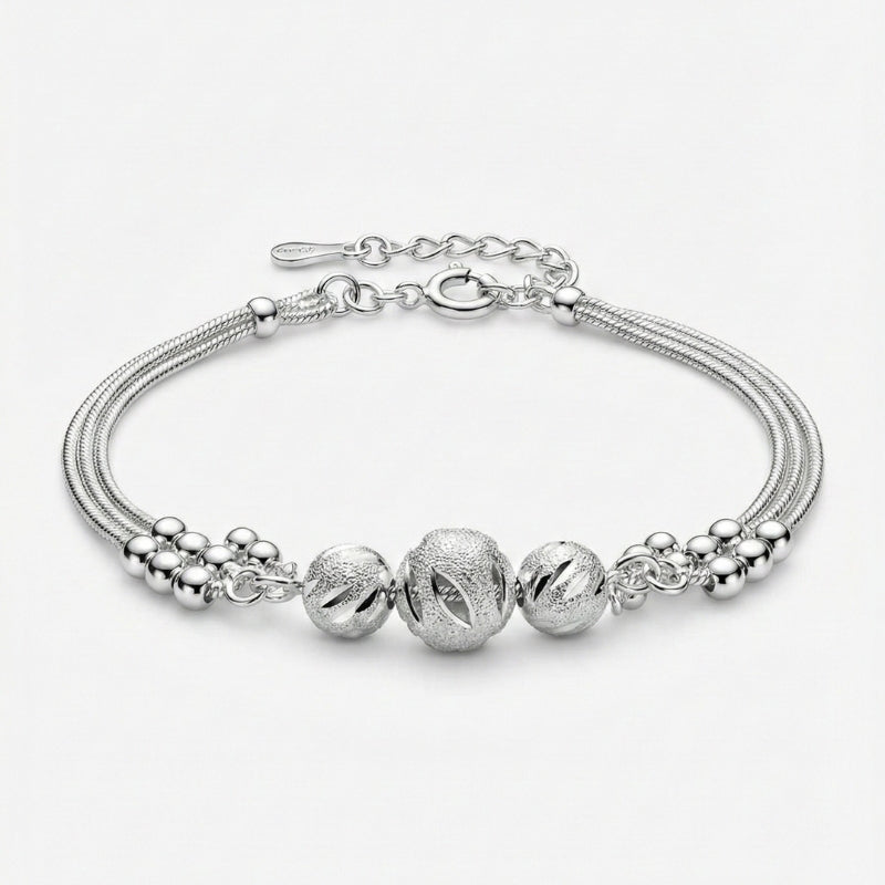 Damenarmband mit mehreren feinen Metallsträngen und dekorativen Zierkugeln in silberfarbener Optik, am Handgelenk getragen und in Detailansicht dargestellt